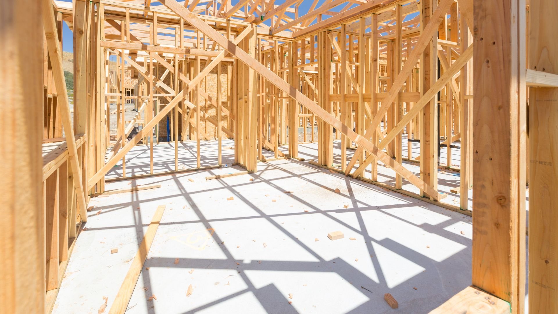 Wooden house frame under construction with exposed beams and blue sky